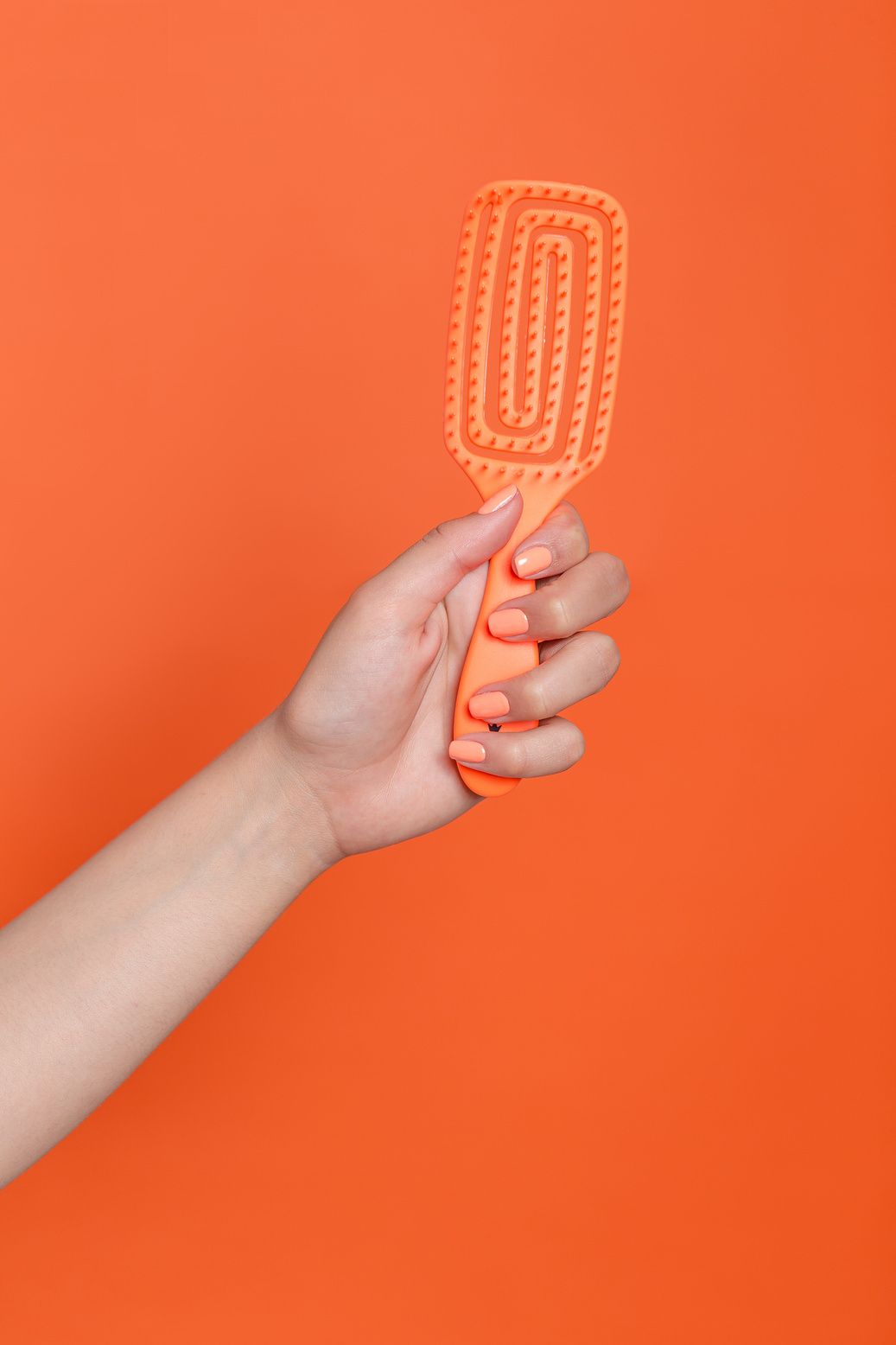 Hand Holding an Orange Hairbrush 